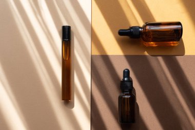 Soyut arka plandaki cam şişeleri taklit et. Kahverengi, bej, turuncu renkler. Çizgili gölgeler, güneş ışığından nesnelerin üzerine düşer. Vücut bakımı kavramı, güzellik endüstrisi.