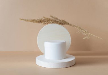 Tahta geometrik podyumda kozmetik ambalaj için beyaz kavanoz modeli. Güzellik ürünlerinin sunumu. Yakın plan, tek renkli arkaplan.