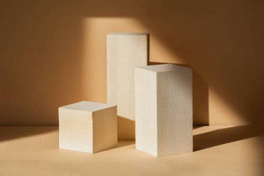 Ürünleri göstermek için tahta geometrik figürlerden yapılmış. Güzellik ürünlerinin sunumu için 3D podyum kavramı. Bej üniforma arka planında doğal nesneler.