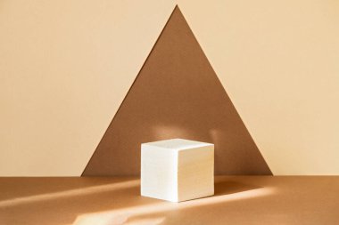 Bir üçgen şeklinde soyut kahverengi-bej arka planda ürünleri sergilemek için kare ahşap 3D podyum. Kozmetik ürünlerin sunumu kavramı. Görüntü için geometrik kaide.
