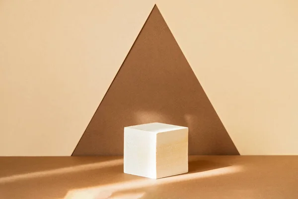 Bir üçgen şeklinde soyut kahverengi-bej arka planda ürünleri sergilemek için kare ahşap 3D podyum. Kozmetik ürünlerin sunumu kavramı. Görüntü için geometrik kaide.