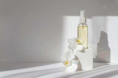 Orkide çiçekleriyle çevrili beyaz geometrik 3d podyum üzerindeki cam şişenin bir kopyası. Ürün gösterileri, spa tedavileri kavramı.