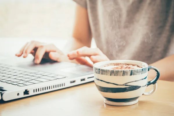 Close up de xícara de café com a mão mulher usando o conceito labtop para freelance (luz macia com filtro vintage ) — Fotografia de Stock