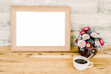 Boş resim çerçevesi üzerinde tablo, çiçek vazolar ve kahve bardağı.