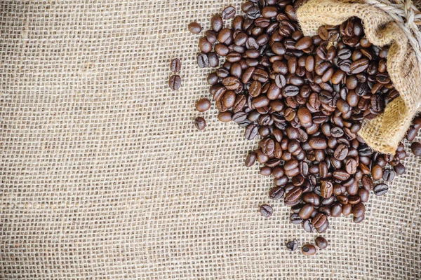 Kaffebönan i säck säck på säckväv bakgrund — Stockfoto