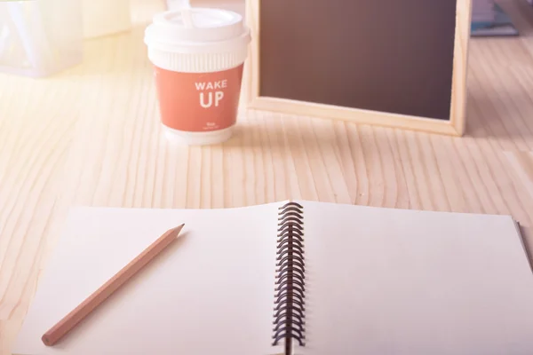 Carta taccuino bianco con matita e tazza di caffè caldo sveglia messaggio sulla scrivania filtro tono caldo — Foto Stock