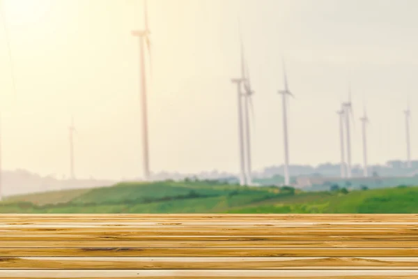 Wooden tables overlooking blurred wind farms energy turbines background — Stock Photo, Image