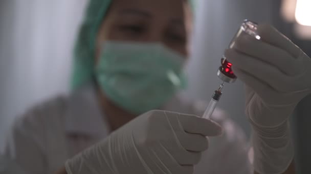 Les mains du médecin remplissent la seringue avec le flacon de médicament sur les mains d'une infirmière, le médecin préparant l'injection au patient. concept de médecine — Video