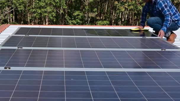 Homme laver et balayer la poussière des panneaux solaires toit de la maison pour renouvelable — Video