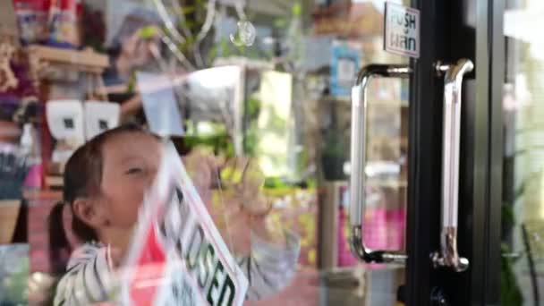 Los niños cuelgan letreros para abrir la tienda para ayudar a los padres a abrir la tienda para el cliente de bienvenida en la mañana — Vídeos de Stock