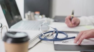 Hekim muayene odasındaki masada steteskop. Doktor hasta için reçete ya da kayıtlar yaz. Sağlık sigortası konsepti