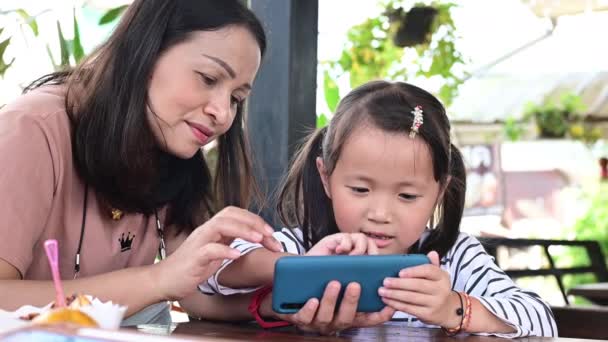 Šťastná matka a dcera hrát hry na smartphone