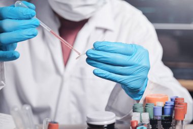 Modern bir laboratuvarda çalışan bilim adamı, laboratuardaki mikroskop için cam slayta bir damla sıvı uygular. Tıbbi araştırmacı kavramı