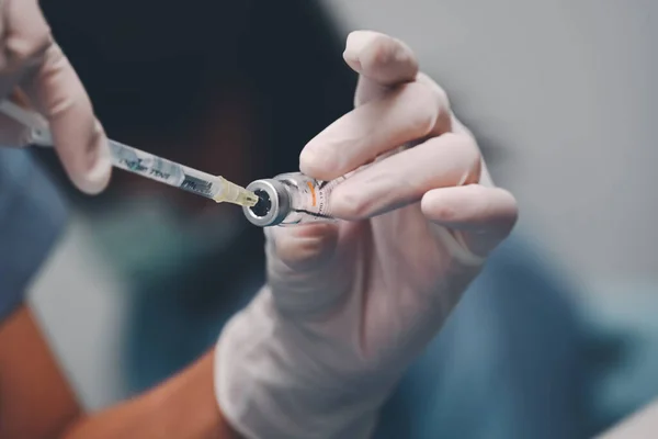 医生使用注射器将COVID-19疫苗从瓶中取出，可以帮助阻止大流行，COVID-19疫苗可以帮助减少新的大肠病毒在人与人之间的传播 — 图库照片