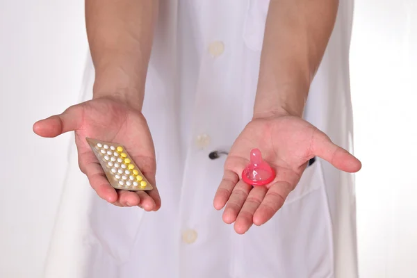 Pílulas contraceptivas na mão do médico, conceito para escolher entre contraceptivos orais ou preservativos . — Fotografia de Stock