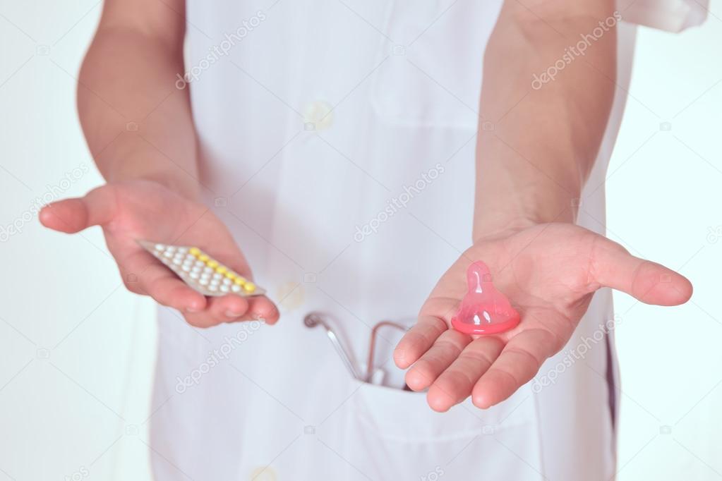 Condoms pills in hand of doctor,Concept for Choose between oral contraceptives or condoms.