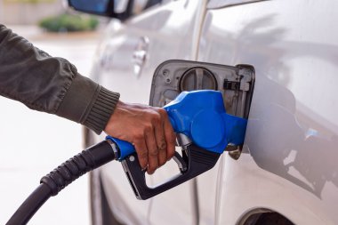 Men hold Fuel nozzle to add fuel in car at gas station clipart