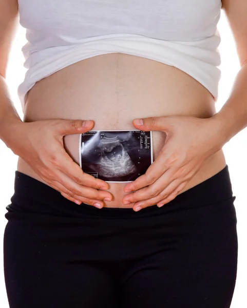 Primer plano de la mujer embarazada sosteniendo ultrasonido en su barriga — Foto de Stock