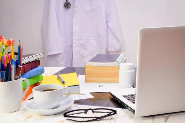 A stack of books on doctor desk and cloth hanging on the wall — Stock Photo, Image