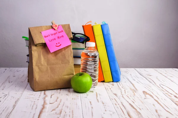 与苹果、 水和书籍的办公桌后它与午餐纸袋请注意 — 图库照片