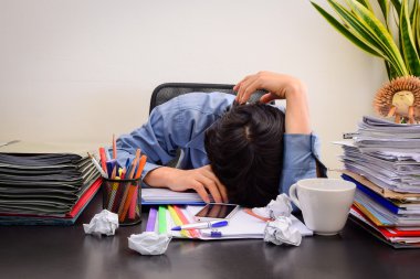 Businessman asleep at office desk with finance sheet calculator and coffee.