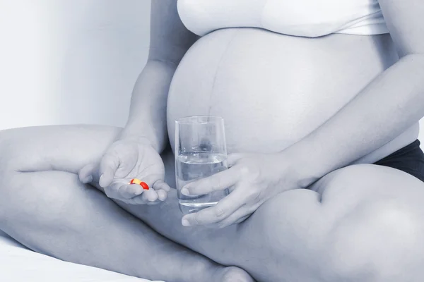 Pregnant woman with medicine pill in hand — Stock fotografie