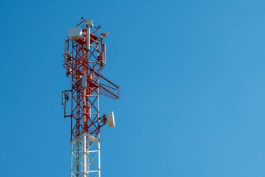 Güneşli günlerde kablosuz antenli cep telefonu kulesi. Anten Telefon ve Telekomünikasyon Kulesi 'nin mavi bir gökyüzü arkaplanı ve metin için yeri var. Arkaplan olarak kullanılabilir.
