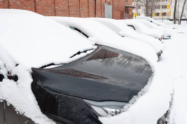 Şehrin yerleşim bölgesindeki karla kaplı bir otoparkta kalın bir kar tabakasıyla kaplı arabalar.