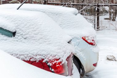 Şehrin yerleşim bölgesindeki karla kaplı bir otoparkta kalın bir kar tabakasıyla kaplı arabalar.