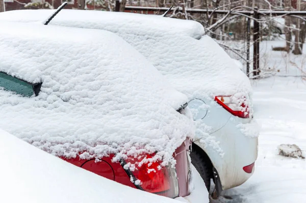 Cars covered with a thick layer of snow in a snow-covered street Parking lot in a residential area of the city