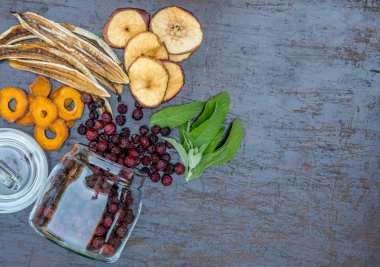 Dilimlenmiş kurutulmuş elma, kayısı ve muz, karanlık bir masada cam bir kavanozda kurutulmuş kiraz. Kurutucuda kurutulmuş meyve pişirme konsepti.