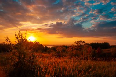 Günbatımında renkli sonbahar manzarası, güneşli tepelerin manzarası, aşağıdaki nehir ve ufuktaki sisli mesafe.