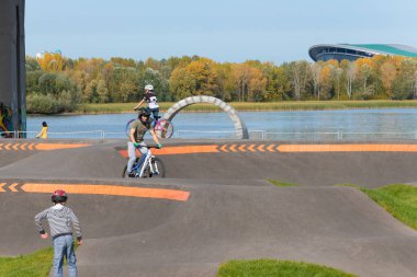 Kazan, Rusya-Eylül 2020: Kulubedeki şehir parkında, motosikletli, kaykaylı ve bisikletli koruyucu miğferli çocuklar ve gençler sürüş alanında.