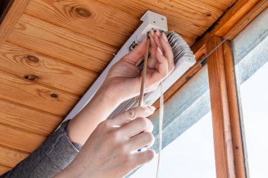 Tornavidayla bir kadının ellerine yakın çekim, beyaz plastiği vidalayan bir kadın tahta tavanı kör ediyor..