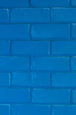 Eski bir tuğla duvar, maviye boyanmış, güneşin eğimli ışınlarıyla aydınlatılmış..