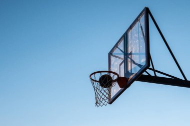 Mavi gökyüzüne karşı çemberin içinde bir basket topu.