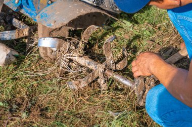 Tanınmayan bir çiftçi el yapımı bir sabanı tamir ediyor. Tarım makineleri: Bahçedeki ekin için ekici, motorlu el sabanı. Gerçek aktivitenin otantik görüntüsü