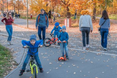 Kazan, Rusya - 03 Ekim 2020: Güneşli bir sonbahar gününde çocuklar ve gençler kentin parkında scooter ve bisiklete biniyorlar