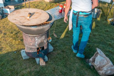Kazan, Rusya - 03 Ekim 2020: ahşap bir kapakla kaplanmış, demir bir fıçıdan yapılmış odun sobası üzerinde pilav bulunan büyük bir kazan. Pilaf şehir parkına ziyaretçiler için hazırlandı..
