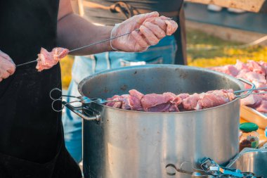 Barbekü şişinde et yiyen bir adamın elleri. Şişte çiğ etin yakın plan görüntüsü. Sokak yemekleri festivali.