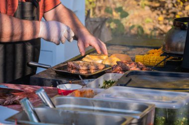 Malzemelerden hamburger pişiriyorum. Profesyonel bir şef hamburger hazırlar. Şehir parkında barbekü festivali. Sokak Fast food.