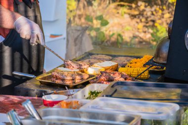 Malzemelerden hamburger pişiriyorum. Profesyonel bir şef hamburger hazırlar. Şehir parkında barbekü festivali. Sokak Fast food.