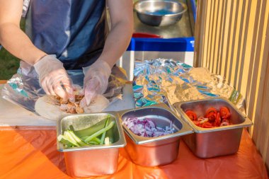 Profesyonel bir şef jiroskopları doldurur. Şehir parkında barbekü festivali. Yunan mutfağı, sokak fast food.