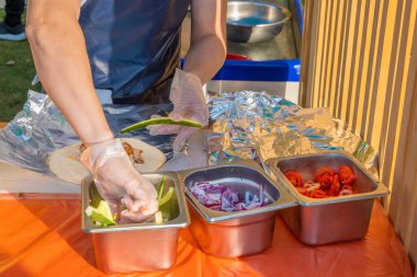 Profesyonel bir şef jiroskopları doldurur. Şehir parkında barbekü festivali. Yunan mutfağı, sokak fast food.