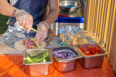 Profesyonel bir şef jiroskopları doldurur. Şehir parkında barbekü festivali. Yunan mutfağı, sokak fast food.