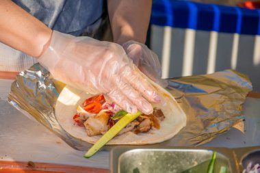 Profesyonel bir şef jiroskopları doldurur. Şehir parkında barbekü festivali. Yunan mutfağı, sokak fast food.