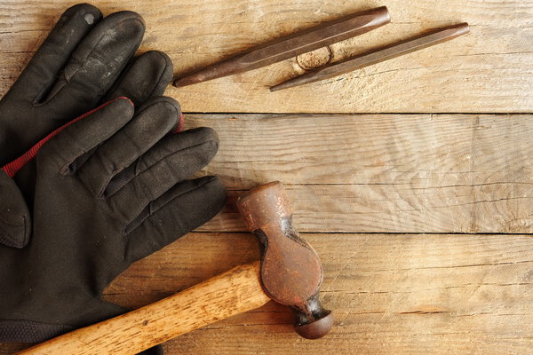 Sledgehammer,leather gloves and Punch on wood Background. Top View of Sledge Hammer with Wooden Handle,black leather gloves and punch.