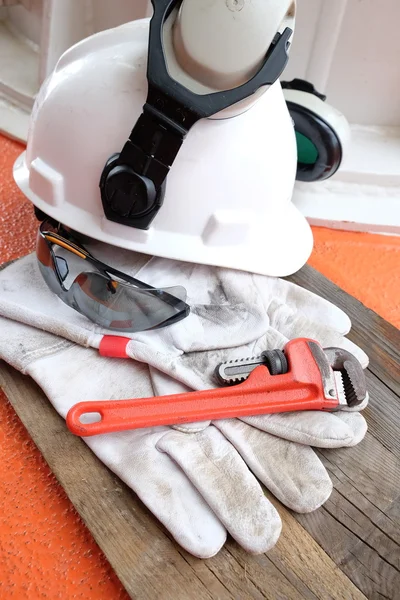 Standart inşaat güvenlik ekipmanları. Kask, koruyucu gözlük, deri eldiven ve beyinameliyatı ahşap arka plan üzerinde.