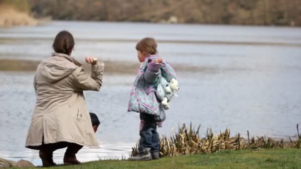 Jeune mère et sa fille s'amusent près de la rivière . — Video