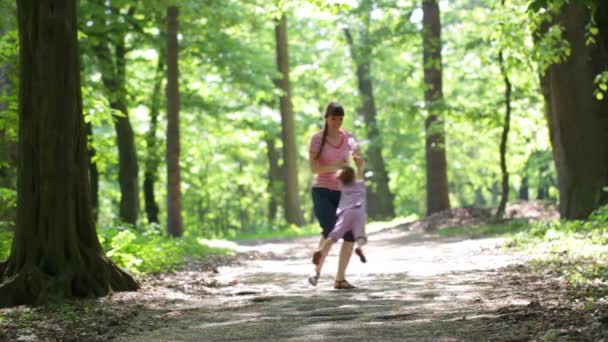 Young mother with little daughter walking in the park — Stock Video